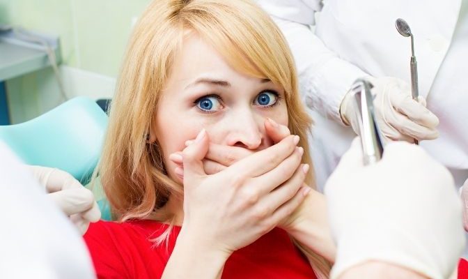 woman scared at dentist visit, siting in chair