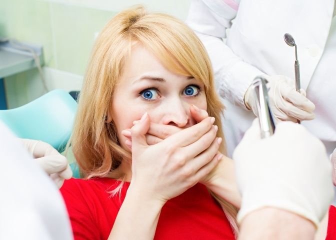 woman scared at dentist visit, siting in chair